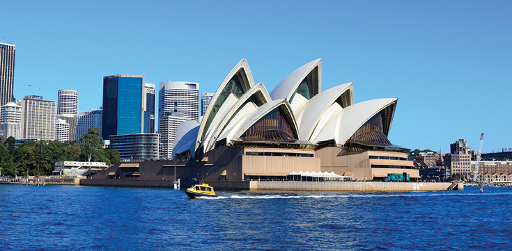 View of city skyline with the Sydney opera house on the water.
